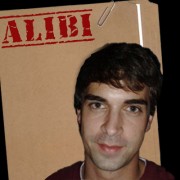 Man with dark hair and eyebrows in front of a manila folder stamped "Alibi"